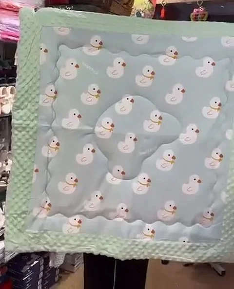 A pastel blue muslin baby blanket with a white duck print.